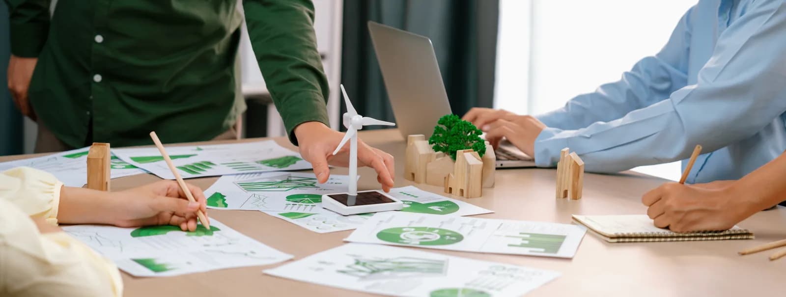 Green business meeting with windmill model, eco-city wooden blocks and environmental documents